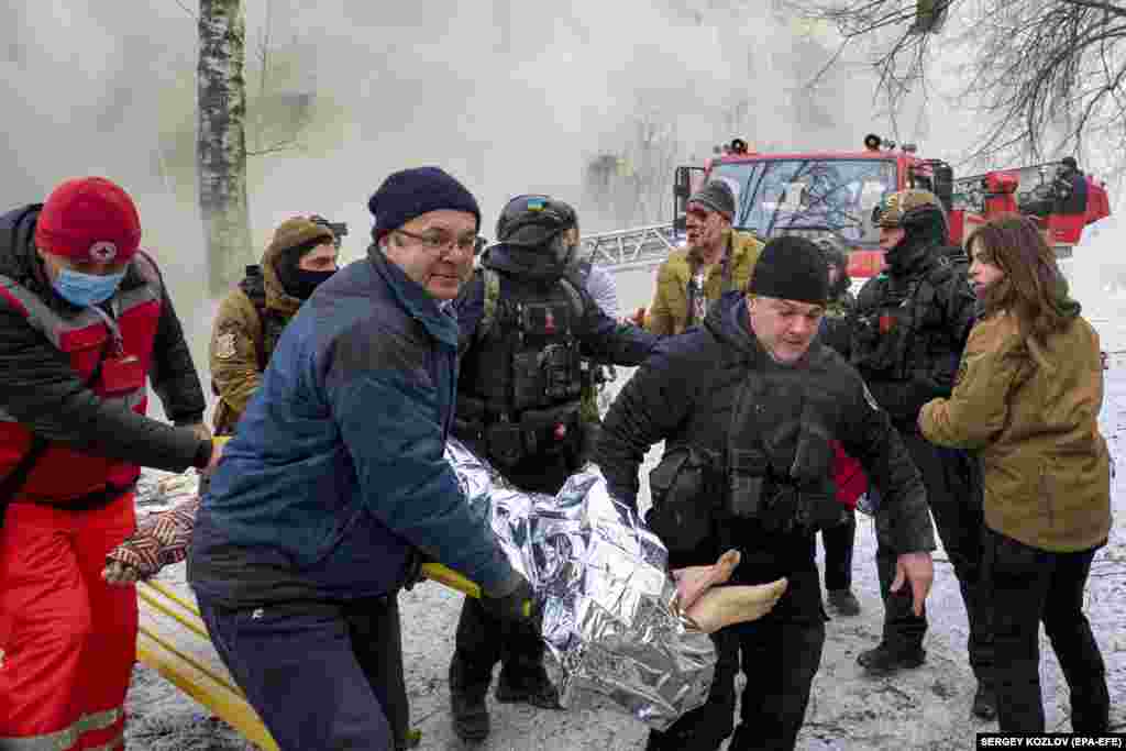 Ukrainian rescuers carry an injured woman from the damaged and smoldering residential building.