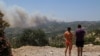 Švicarski turisti promatraju šumski požar koji gori u blizini sela Archangelos, otok Rodos, Grčka, 24. juli