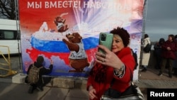 Женщина фотографируется во время мероприятия, посвящённого девятой годовщине аннексии Крыма Россией, Санкт-Петербург, 18 марта 2023 года
