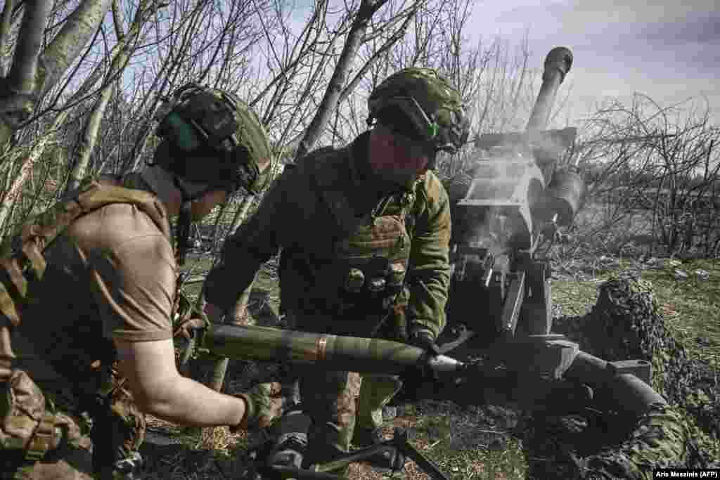 Ukrainian soldiers load a shell into a M119 105-mm howitzer. &nbsp;