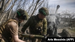 Українські військові завантажують снаряд у британську 105-мм гаубицю М119 на позиціях біля Бахмуту, 23 березня 2023 року