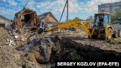 Місцеві жителі розчищають завали та лагодять пошкоджені труби внаслідок ракетного обстрілу селища Золочів Харківської області, Україна, 14 травня 2023 року