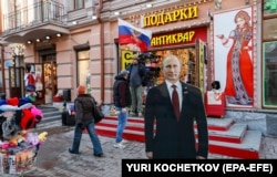 People walk past a cardboard cutout of Putin on a street in Moscow on March 13. “There is no way you can call this an election. And the majority of the population understands this perfectly,” one analyst said of Russia’s March 15-17 presidential vote.
