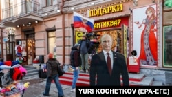 Ljudi prolaze pored kartonskog lika ruskog predsjednika Vladimira Putina na ulici u Moskvi, 13. marta 2024.