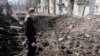Житель Авдеевки обследует воронку от очередного удара российской артиллерии