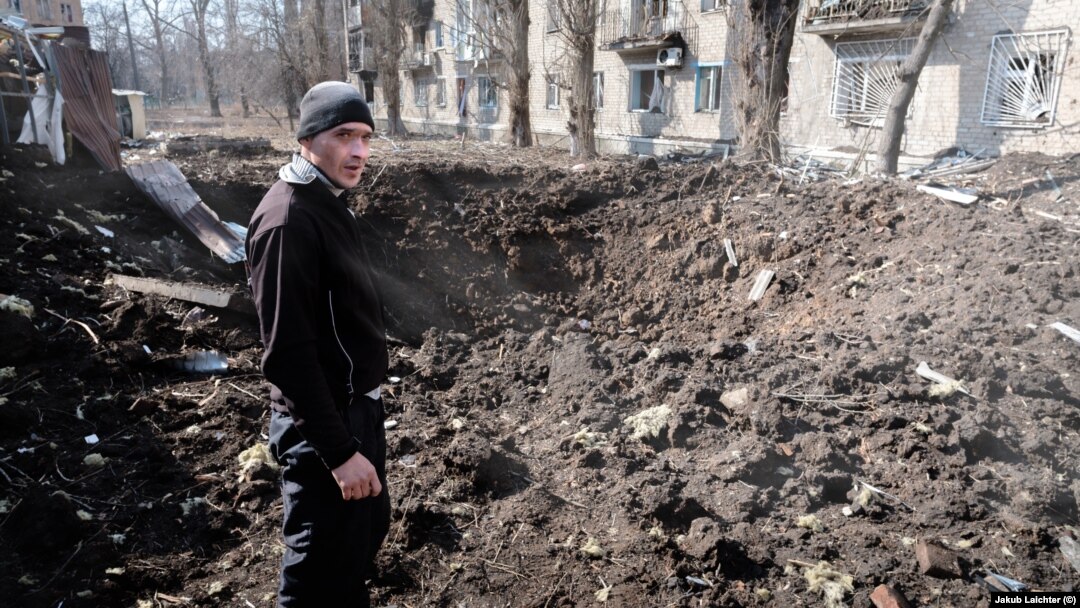 A man in Avdiyivka inspects a fresh crater after Russian shelling in the center of his hometown.