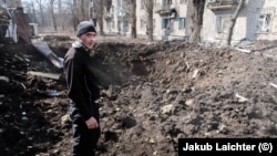 Un bărbat din Avdiivka analizează un crater apărut recent, după ce rușii au bombardat centrul orașului. 