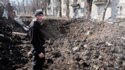 Un bărbat din Avdiivka analizează un crater apărut recent, după ce rușii au bombardat centrul orașului. 