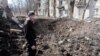 Një burrë në Avdijivka qëndron pranë dëmeve të shkaktuara nga një predhë ruse në qendër të vendlindjes së tij. 