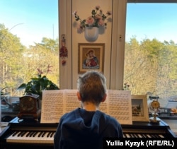 Син Христини грає на піаніно у поселенні для українських біженців