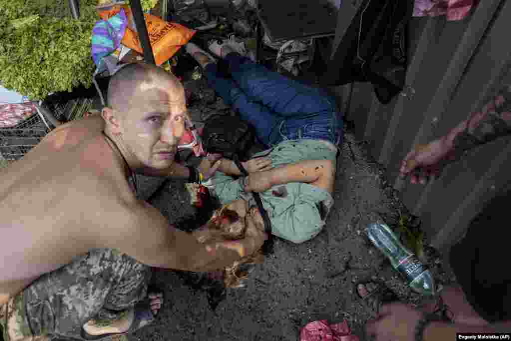 Чоловік перевіряє пульс жінки, яка загинула під час нападу на ринок у Костянтинівці. Москва ж далі заперечує обстріли цивільних людей в Україні