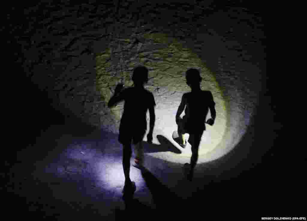 Children play in the dark with flashlights in a residential area during an electricity blackout in Kyiv.