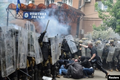 Protestuesit serbë duke goditur pjesëtarë të misionit të NATO-s në Kosovë, KFOR, me shkopinj, në hyrje të ndërtesës komunale në Zveçan, komunë në veri e banuar me shumicë serbe. (Foto: Reuters)