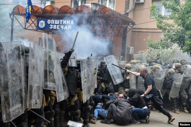 Protestuesit serbë duke goditur pjesëtarë të misionit të NATO-s në Kosovë, KFOR, me shkopinj, në hyrje të ndërtesës komunale në Zveçan, komunë në veri e banuar me shumicë serbe. (Foto: Reuters)