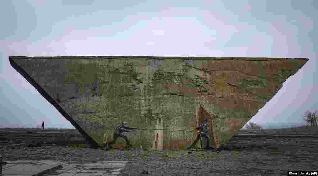 A mural on a memorial depicts Ukrainian and Russian soldiers in a tug-of-war in Izyum, Kharkiv region, Ukraine.