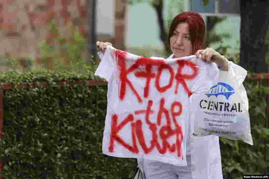 Një grua mban një bluzë ku shkruan &quot;KFOR-i vrasësi&quot;, para objektit të komunës në qytetin e Zveçanit, në veri të Kosovës, të mërkurën më 31 maj 2023.&nbsp;