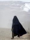 AFGHANISTAN - WEATHER - An Afghan burqa-clad woman walks along a street amid fog in Fayzabad district at Badakhshan province on March 11, 2024