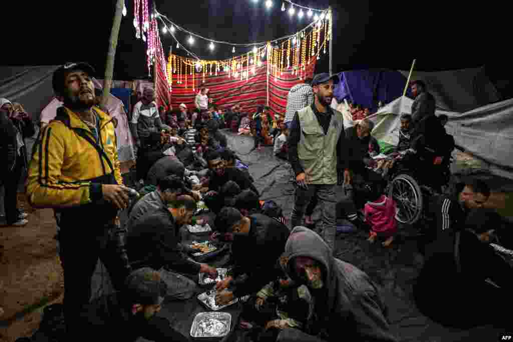 Palestinezët duke ngrënë iftar në një kamp refugjatësh në Rafah, mes luftimeve të vazhdueshme midis Izraelit dhe grupit militant Hamas, të cilësuar si organizatë terroriste nga Shtetet e Bashkuara dhe Bashkimi Evropian. Kreu i OKB-së, Guterres, vlerësoi se vrasja e civilëve në Gaza dhe shkatërrimi i territorit palestinez është në një nivel të paprecedent në shtatë vjetët e fundit sa ka qenë ai në krye të Kombeve të Bashkuara.