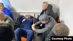 Bektur Asanov lies on a chair after one of the court hearings in the Kempir-Abad case. 