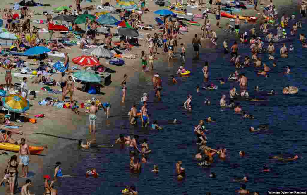 People relax on a city beach by the Dnipro River on an extremely hot summer day in Kyiv.