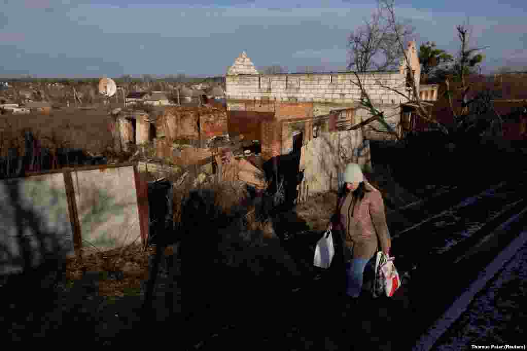 A local woman carries groceries past houses that were damaged during fighting. Unlike those living in urban areas, children in villages near the front often lack schools and in-person contact. The Ukrainian volunteer collective Base UA is trying to address this issue by sending teams of volunteers to the Donetsk region for stints of several weeks at a time.&nbsp;