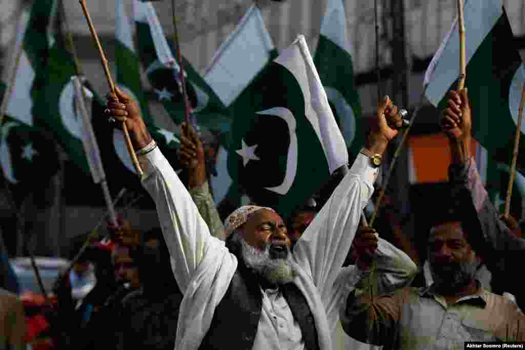 Men wave flags as they chant slogans during a rally in support of the Pakistani Army in Karachi.