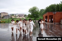 High school girls run across the courtyard of Stepanakert’s Cathedral after their graduation ceremony on May 26.