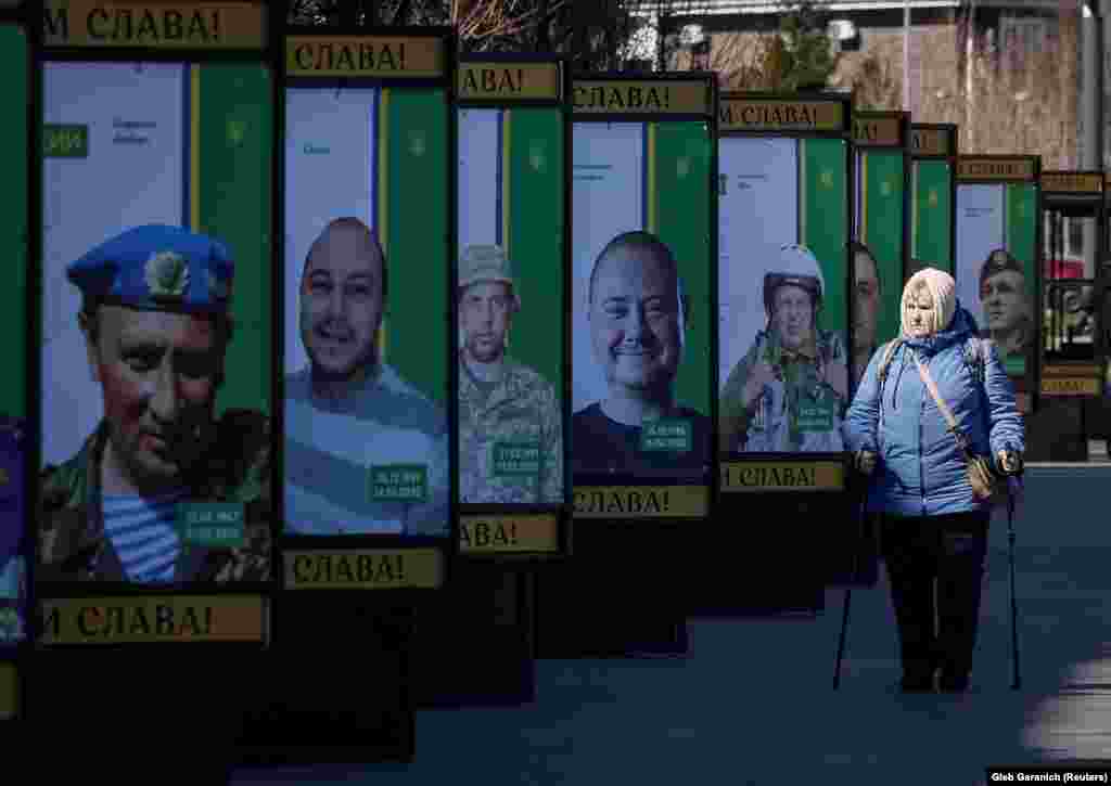 Жінка проходить повз білборди з фотографіями українських воїнів, які загинули, захищаючи Україну. Буча, Київщина, 30 березня 2023 року