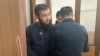 Обвиняемый в «пропаганде терроризма» житель Семея Чингиз Альпиев и обвиняемый вместе с ним Ринат Алиев после заседания покидают зал судебного заседания в сопровождении сотрудников сил безопасности. И Альпиев, и Алиев отвергают предъявленные им обвинения. Семей, 27 марта 2023 года