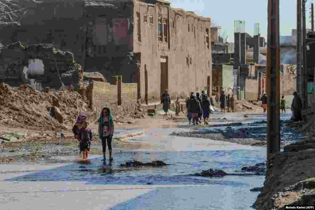 Afghan residents walk through a flooded street following the flash floods. Foreign aid to Afghanistan has drastically decreased since the fall of the U.S.-backed government and the return of the Taliban, making the already destitute country less prepared to handle natural disasters.