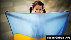 Маленька дівчинка з українським прапором на мітингу українських біженців, де вони закликали світових лідерів визнати Росію державою-спонсором тероризму, Бухарест 2023 рік. (фото ілюстративне)