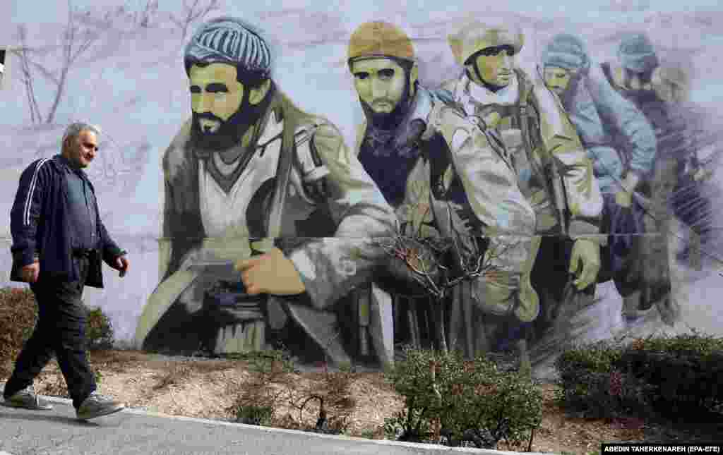 An man walks past a mural of Islamic Revolutionary Guards Corps soldiers on a street in Tehran.
