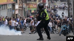 A riot police officer uses tear gas against demonstrators during a protest by opponents of Venezuelan President Nicolas Maduro's government in the Catia neighborhood of Caracas on July 29, a day after the Venezuelan presidential election. 