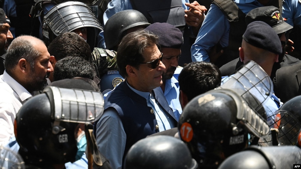 Police officers escort former Pakistani Prime Minister Imran Khan (center) as he arrives at the high court in Islamabad on May 12.