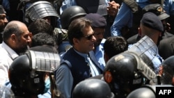 Police officers escort former Pakistani Prime Minister Imran Khan (center) as he arrives at the high court in Islamabad on May 12.