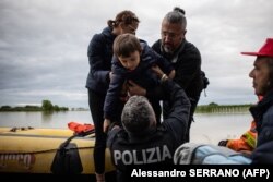 Një fëmijë duke u shpëtuar nga vërshimet në Masa Lombardia më 17 maj.