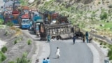 People look at a charred vehicle near a collapsed railway bridge a day after a blast by separatist Baloch Liberation Army militants at Kolpur in Bolan district, Balochistan Province, on August 27.