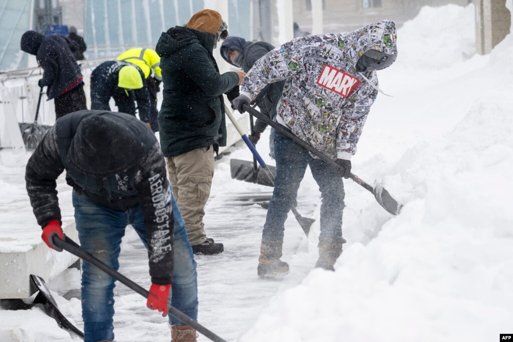 Punëtorë dhe vullnetarë duke pastruar një trotuar nga bora, Ajova, më 13 janar 2024.
