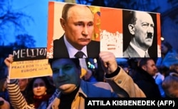 Плакат с изображением российского президента Владимира Путина и Адольфа Гитлера на акции возле посольства РФ в Венгрии во вторую годовщину полномасштабного вторжения России в Украину. Будапешт, 24 февраля 2024 года