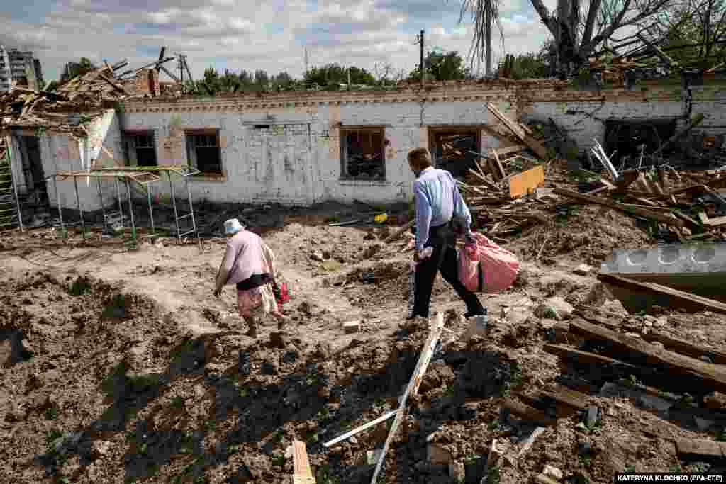 Люди проходять повз зруйновану будівлю школи. Наразі в Оріхові залишилося близько 700 жителів. Залишаючись у місті, вони ризикують своїм життям через майже щоденні ракетні та артилерійські обстріли РФ