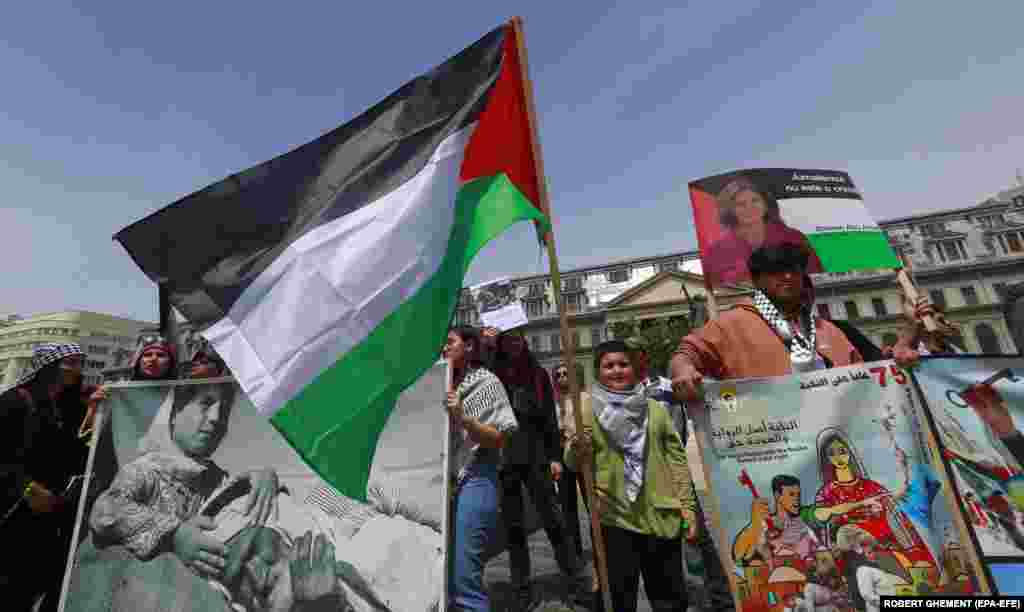 Protesters wave Palestinian flags and banners during a pro-Palestinian demonstration at University Plaza in downtown Bucharest.