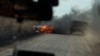 Українські військові проїжджають повз палаючу машину біля прифронтового міста Авдіївка, листопад 2023 року 