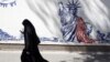 An Iranian woman walks past an anti-U.S. mural around the former U.S. Embassy in Tehran.