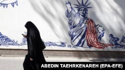 An Iranian woman walks past an anti-U.S. mural around the former U.S. Embassy in Tehran.