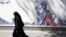 An Iranian woman walks past an anti-U.S. mural around the former U.S. Embassy in Tehran.