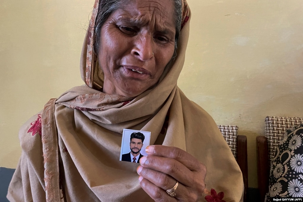 Në këtë foto të bërë më 20 qershor 2023, Tazeem Pervaiz, nëna e emigrantit Taquir Pervaiz, i cili është zhdukur pasi një anije peshkimi e mbingarkuar u përmbys dhe u fundos në Detin Jon, qan ndërsa mban një foto të djalit të saj në fshatin Bandli, në Kashmirin e administruar nga Pakistani.&nbsp; Vdekja varet mbi fshatin e Pakistanit Bandli si një qefin, ndërsa banorët marrin lajmet se deri në 24 të rinj vendas mund të jenë në mesin e qindra të mbyturve në tragjedinë e javës së kaluar me varkën e emigrantëve grekë.&nbsp;