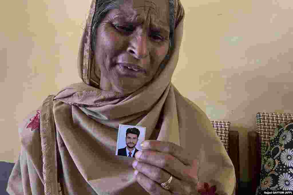 Tazeem Pervaiz, the mother of migrant Taquir Pervaiz, who is missing after an overloaded trawler capsized and sank in the Ionian Sea, weeps while holding a picture of her son in Bandli village in Pakistan-administered Kashmir.