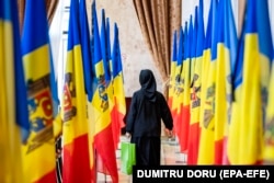 Pravoslavna monahinja hoda među nacionalnim zastavama Moldavije.