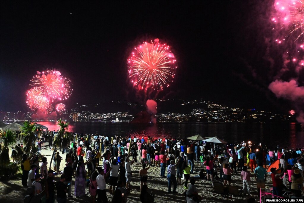 Në gjirin e Akapulkos në Meksikë, banorët shikojnë spektaklin me fishekzjarrë nga një plazh. 