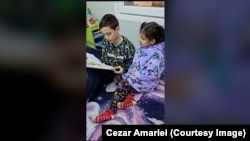 Cristian Iliescu (12 ani) îi citește surorii sale, Esfir Ana Maria (4 ani), în containerul pe care deocamdată îl consideră noua lor casă.